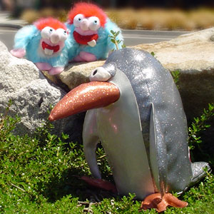 SOft sculpture of a one eyed penguin and furry twins